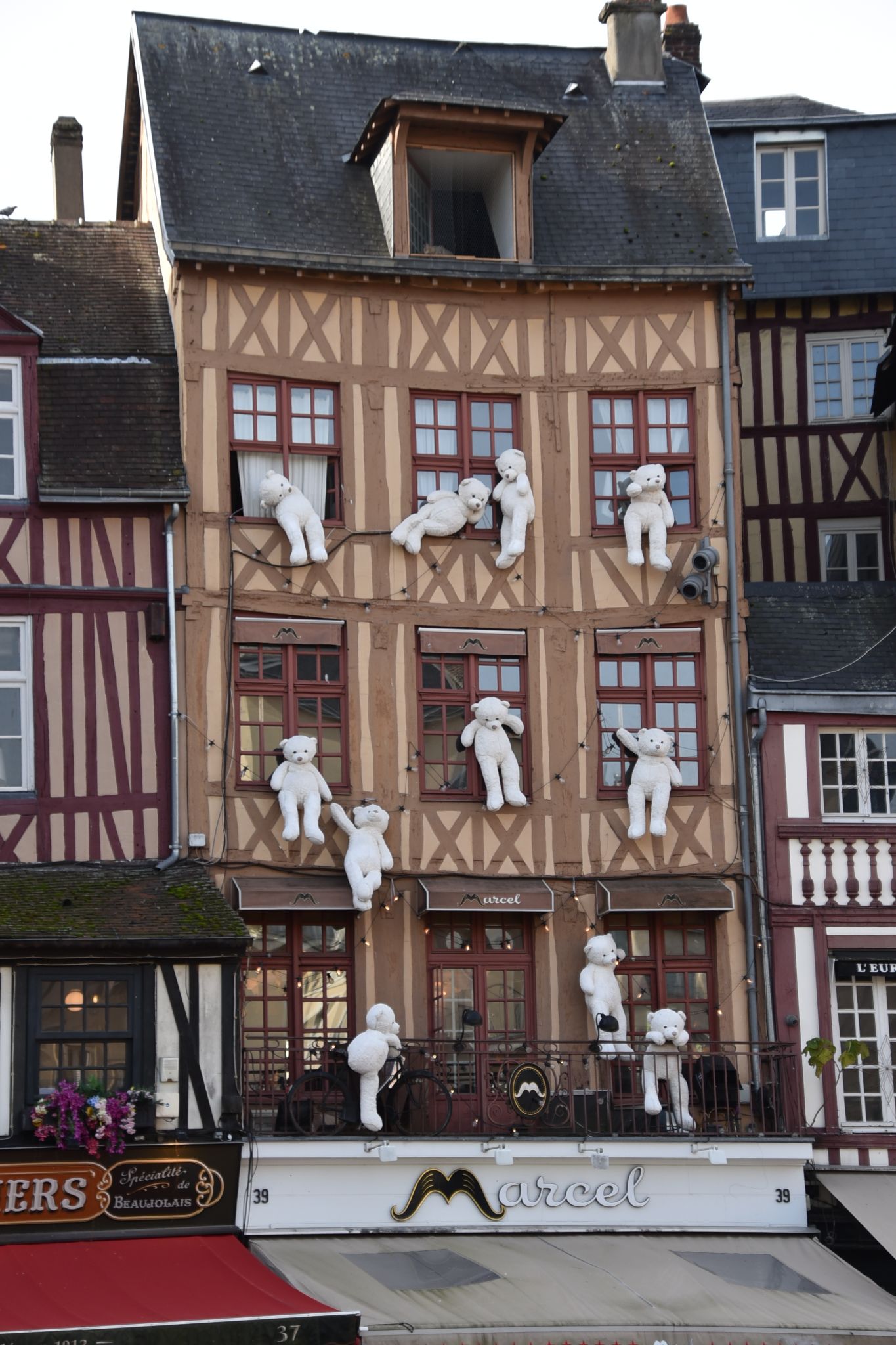 A traditional half-timbered medieval building decorated with large white teddy bears,